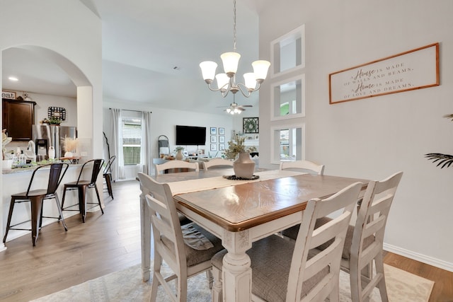 8619 Morning Dove Ln, Baytown, TX 77521 - dining area with a chandelier, arched walkways, light wood-type flooring, a towering ceiling, and baseboards