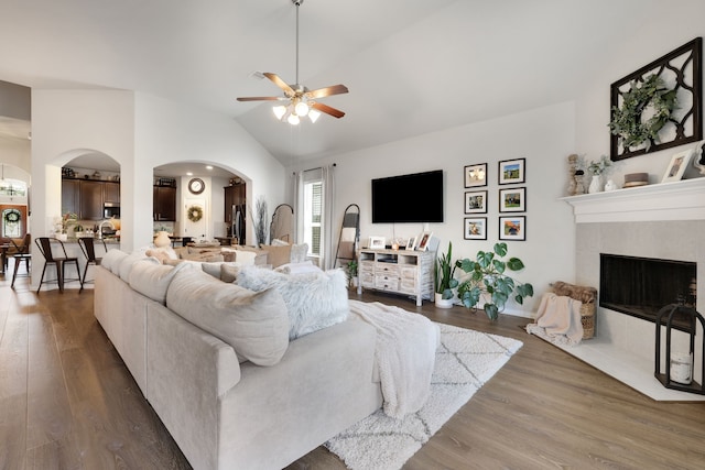 8619 Morning Dove Ln, Baytown, TX 77521 - living room with arched walkways, a ceiling fan, vaulted ceiling, wood finished floors, and a tiled fireplace