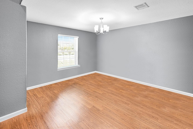 9726 Shimmering Lakes Dr, Rosharon, TX 77583 - empty room with a chandelier, wood finished floors, a textured wall, and baseboards