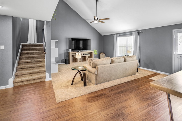 living area featuring ceiling fan, stairs, healthy amount of natural light, wood finished floors, and high vaulted ceiling