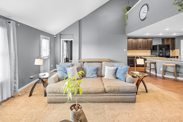 living area featuring wood finished floors, high vaulted ceiling, recessed lighting, and baseboards
