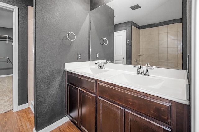 9726 Shimmering Lakes Dr, Rosharon, TX 77583 - bathroom with a textured wall, wood finished floors, double vanity, baseboards, and a shower