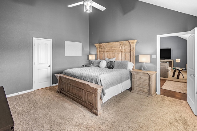 bedroom featuring light carpet, high vaulted ceiling, a ceiling fan, and baseboards