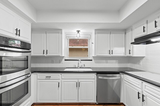 5918 Donwhite Ln, Houston, TX 77088 - kitchen featuring stainless steel appliances, a sink, under cabinet range hood, white cabinetry, and backsplash