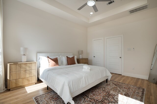 7612 Ave L, Houston, TX 77012 - bedroom with light wood-type flooring, a ceiling fan, baseboards, a raised ceiling, and recessed lighting