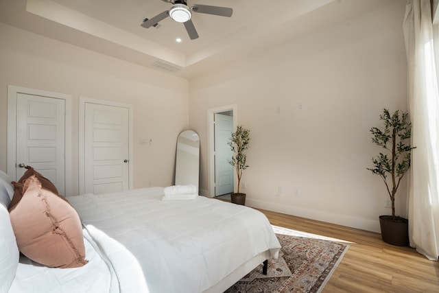 7612 Ave L, Houston, TX 77012 - bedroom with light wood finished floors, baseboards, a tray ceiling, a ceiling fan, and recessed lighting