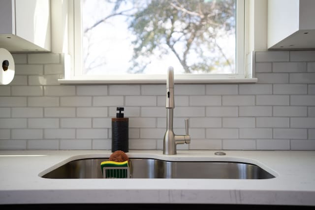7612 Ave L, Houston, TX 77012 - kitchen view of a sink, backsplash, white cabinets, and exhaust hood