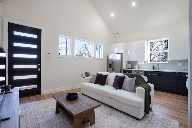 7612 Ave L, Houston, TX 77012 - living room featuring high vaulted ceiling, plenty of natural light, light wood-style flooring, baseboards, and recessed lighting