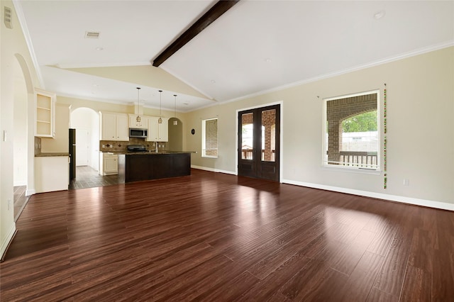 unfurnished living room with arched walkways, dark wood-style flooring, baseboards, and crown molding