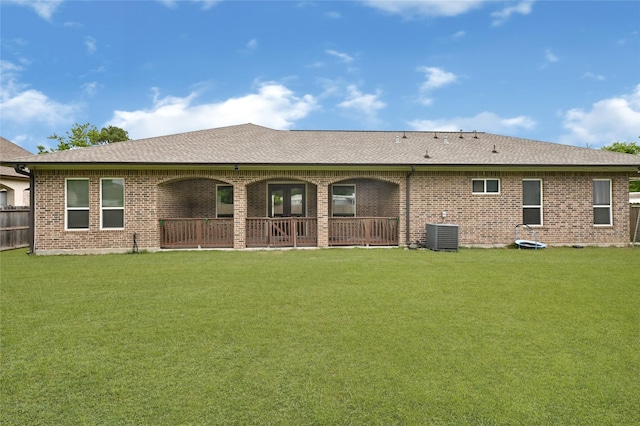 back of house featuring a shingled roof, central AC unit, and brick siding