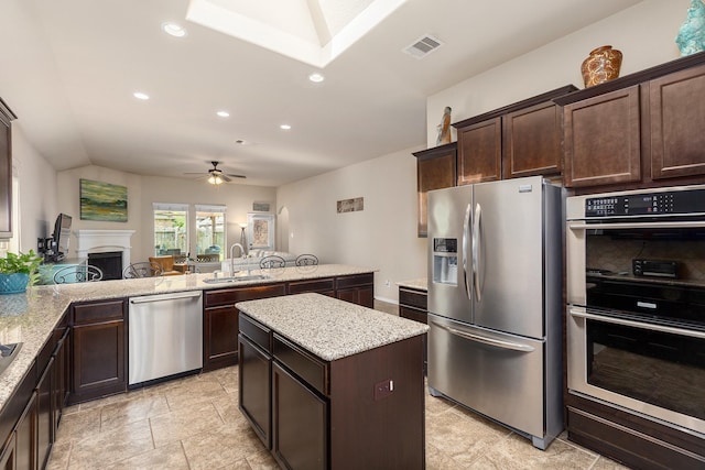 18107 Banpo Ct, Houston, TX 77044 - kitchen featuring appliances with stainless steel finishes, a sink, dark brown cabinetry, recessed lighting, and a kitchen island