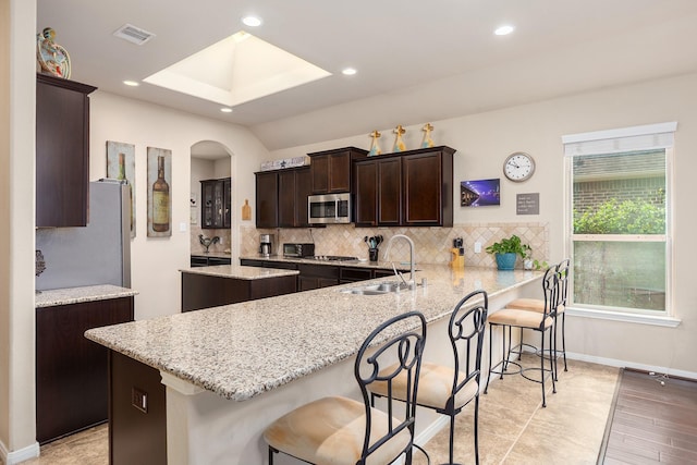 18107 Banpo Ct, Houston, TX 77044 - kitchen with a sink, appliances with stainless steel finishes, dark brown cabinets, a center island, and tasteful backsplash
