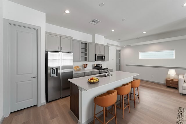 46 Dipping Ln, Houston, TX 77076 - kitchen with stainless steel appliances, gray cabinetry, a sink, light wood-style floors, and a kitchen breakfast bar