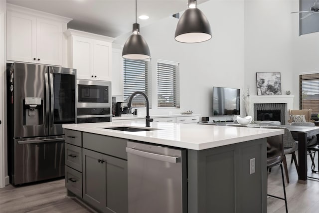 7507 Zion Grove Ct, Katy, TX 77493 - kitchen with appliances with stainless steel finishes, a sink, gray cabinets, a center island with sink, and light countertops