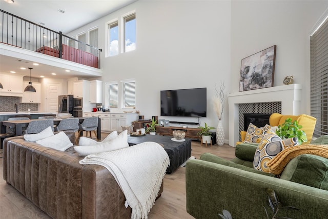 7507 Zion Grove Ct, Katy, TX 77493 - living room featuring a towering ceiling, light wood-type flooring, a tiled fireplace, and recessed lighting