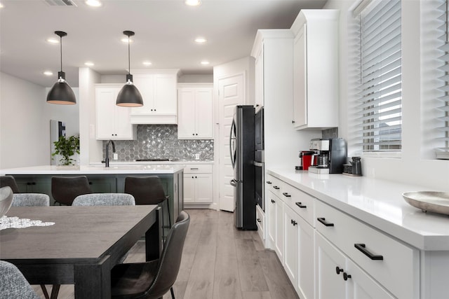 7507 Zion Grove Ct, Katy, TX 77493 - kitchen featuring freestanding refrigerator, white cabinets, light countertops, tasteful backsplash, and light wood-type flooring