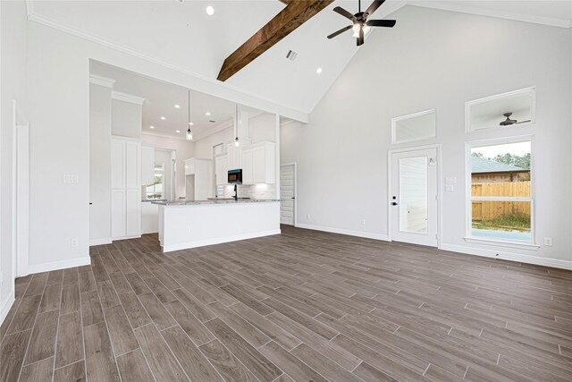 117 Big Spring Dr, Anahuac, TX 77514 - unfurnished living room featuring a ceiling fan, beamed ceiling, high vaulted ceiling, dark wood-type flooring, and baseboards