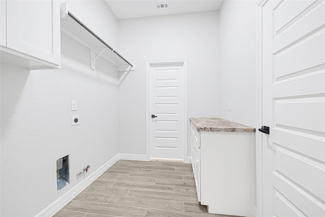 117 Big Spring Dr, Anahuac, TX 77514 - laundry room with gas dryer hookup, hookup for an electric dryer, light wood-style floors, baseboards, and cabinet space