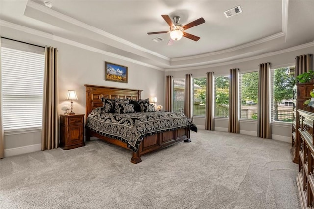 bedroom featuring a tray ceiling, crown molding, light colored carpet, baseboards, and ceiling fan