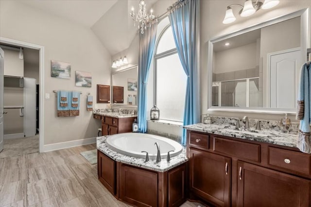 full bath with vaulted ceiling, a stall shower, plenty of natural light, a chandelier, and a bath