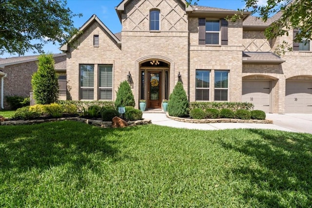 french provincial home with brick siding, a front yard, a garage, concrete driveway, and a shingled roof