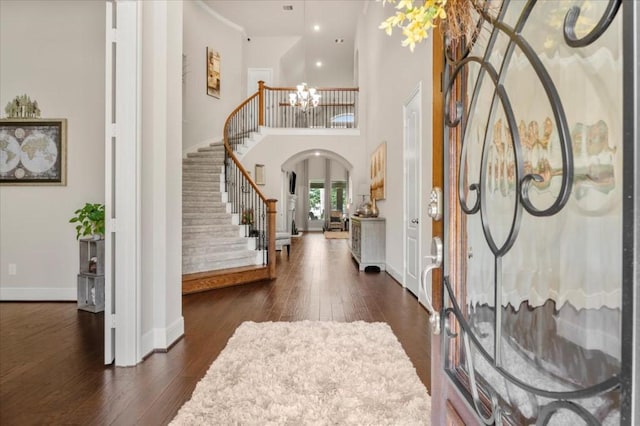 entryway featuring arched walkways, stairs, dark wood-type flooring, baseboards, and a chandelier