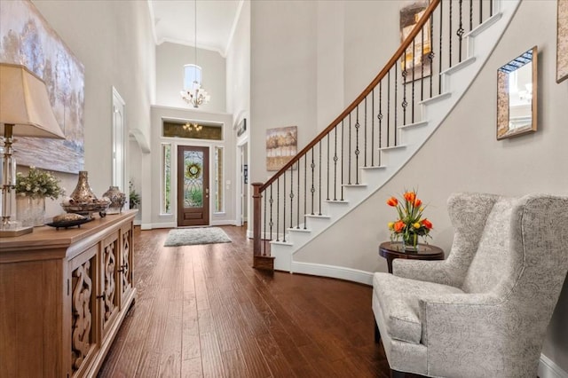 entryway featuring a high ceiling, baseboards, stairway, crown molding, and a chandelier