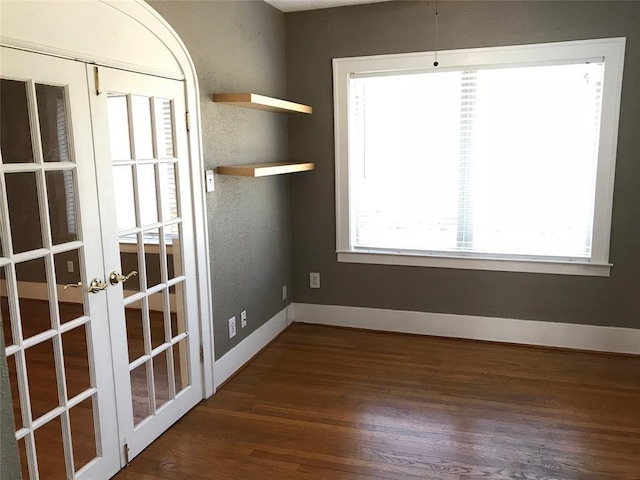 empty room with french doors, wood finished floors, and baseboards