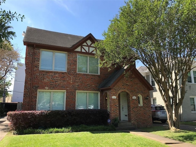tudor house featuring a front yard and brick siding