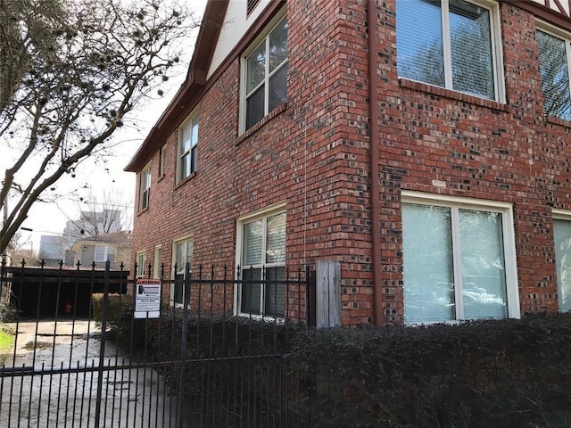 view of side of property with brick siding, fence, and a gate
