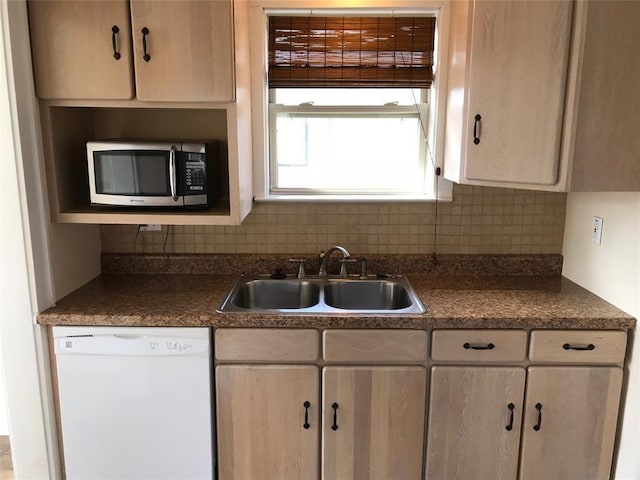 kitchen featuring dishwasher, stainless steel microwave, a sink, tasteful backsplash, and dark countertops