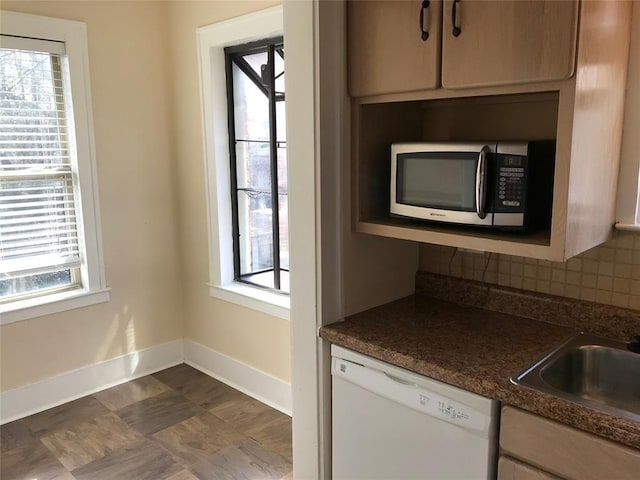 kitchen with dishwasher, stainless steel microwave, baseboards, tasteful backsplash, and dark countertops
