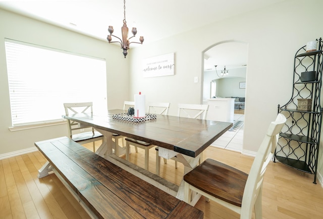 11606 Curry Ridge Ln, Tomball, TX 77377 - dining area featuring a chandelier, arched walkways, light wood-type flooring, and baseboards