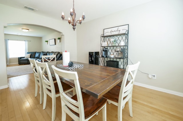 11606 Curry Ridge Ln, Tomball, TX 77377 - dining room with arched walkways, a chandelier, light wood finished floors, and baseboards