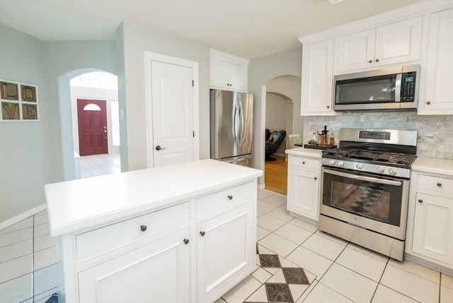 11606 Curry Ridge Ln, Tomball, TX 77377 - kitchen with stainless steel appliances, arched walkways, decorative backsplash, light tile patterned floors, and white cabinetry
