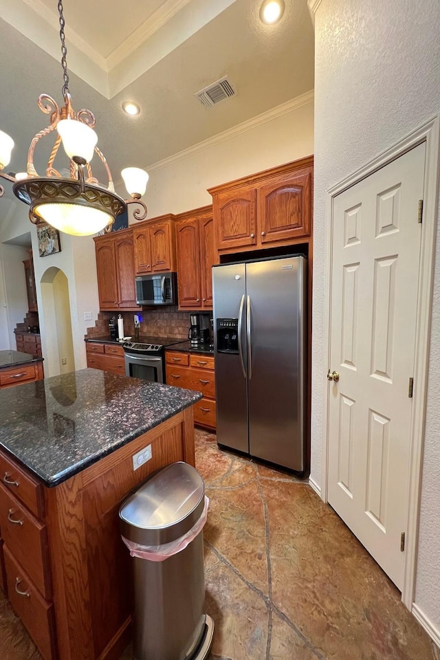 kitchen featuring appliances with stainless steel finishes, ornamental molding, arched walkways, tasteful backsplash, and brown cabinetry