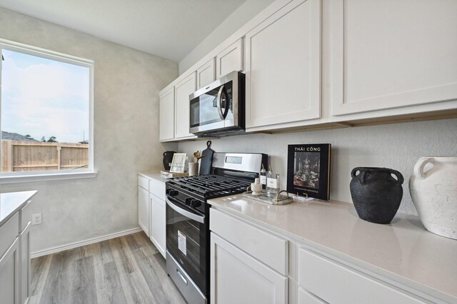 16602 Bobal Path, Houston, TX 77090 - kitchen featuring stainless steel appliances, light countertops, white cabinetry, and light wood-style floors