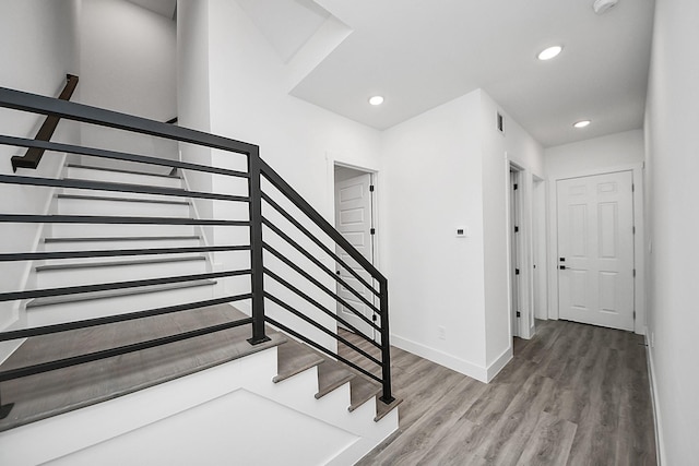 staircase featuring wood finished floors, baseboards, and recessed lighting