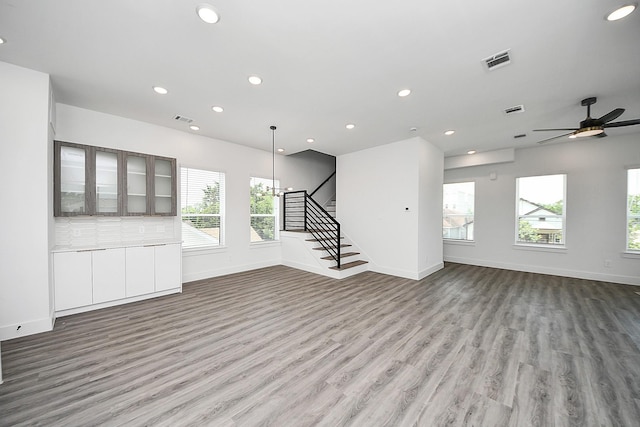 unfurnished living room with wood finished floors, ceiling fan, stairs, baseboards, and recessed lighting