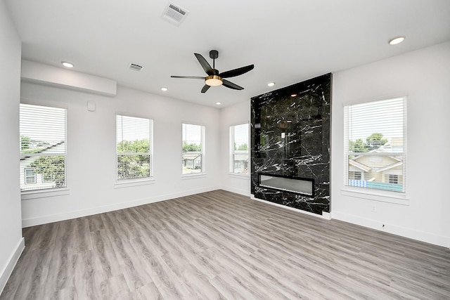 unfurnished living room with wood finished floors, baseboards, recessed lighting, a fireplace, and a ceiling fan