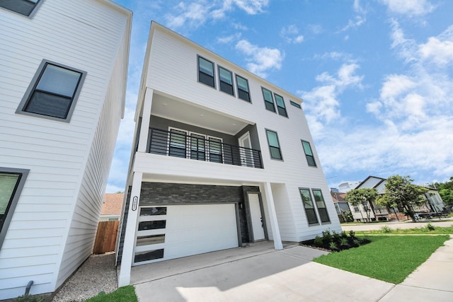 modern home featuring a balcony, an attached garage, concrete driveway, and fence