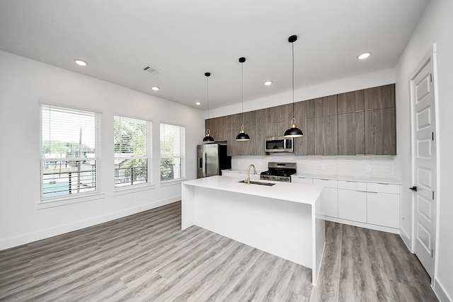 kitchen featuring stainless steel appliances, modern cabinets, a sink, recessed lighting, and light countertops