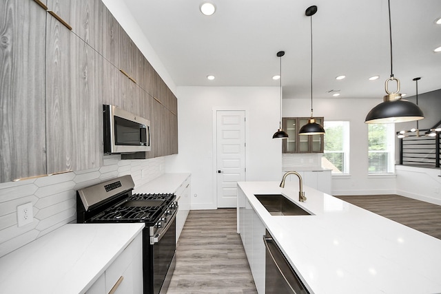 kitchen with appliances with stainless steel finishes, a sink, dark wood-style flooring, modern cabinets, and recessed lighting