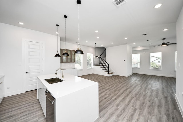 kitchen with a sink, stainless steel dishwasher, baseboards, recessed lighting, and light wood finished floors