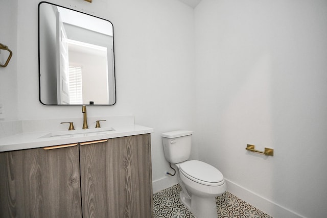 half bathroom with baseboards, toilet, vanity, and tile patterned flooring
