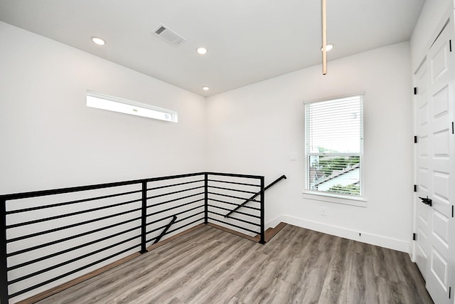 unfurnished room featuring wood finished floors, baseboards, and recessed lighting