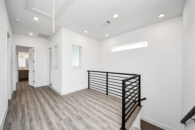 unfurnished room featuring attic access, baseboards, wood finished floors, recessed lighting, and a smoke detector