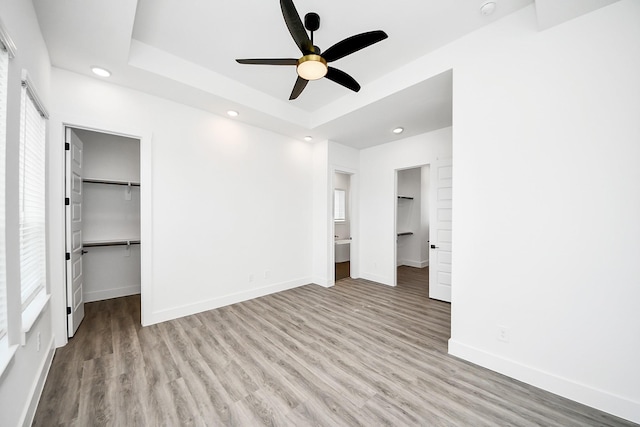unfurnished bedroom featuring a spacious closet, wood finished floors, baseboards, a closet, and recessed lighting