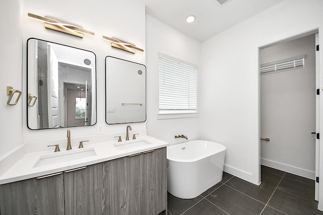 full bathroom featuring a freestanding tub, double vanity, tile patterned flooring, and baseboards