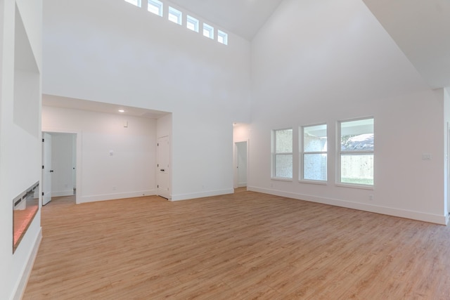 3203 Hemingway Dr, Montgomery, TX 77356 - unfurnished living room with high vaulted ceiling, light wood-type flooring, and baseboards